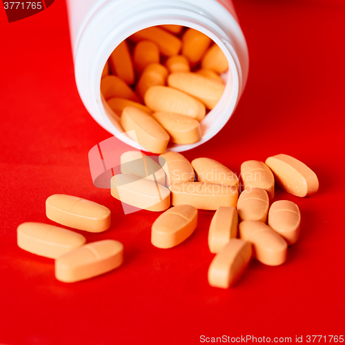 Image of Pills spilling out of pill bottle on red. Top view with copy space. 