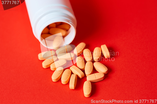 Image of Pills spilling out of pill bottle on red. Top view with copy space. 