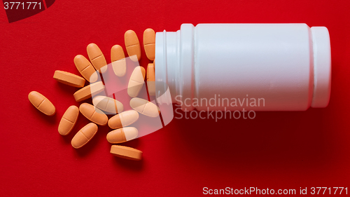 Image of Pills spilling out of pill bottle on red. Top view with copy space. 