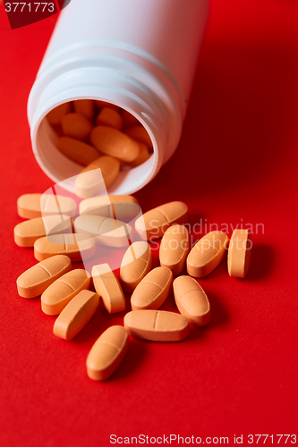 Image of Pills spilling out of pill bottle on red. Top view with copy space. 