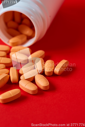 Image of Pills spilling out of pill bottle on red. Top view with copy space. 