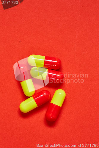 Image of Pills spilling out of pill bottle on red. Top view with copy space. 