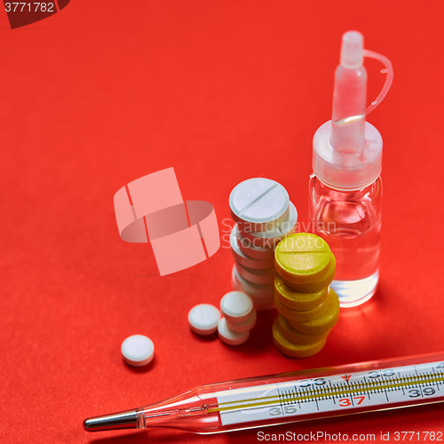 Image of Mercury thermometer and medical pills on background