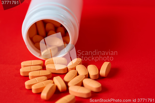 Image of Pills spilling out of pill bottle on red. Top view with copy space. 