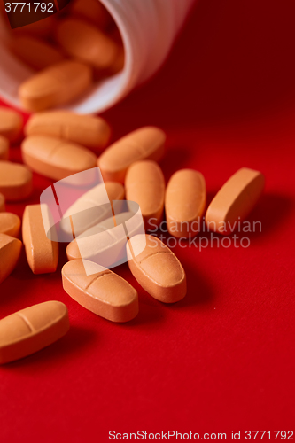 Image of Pills spilling out of pill bottle on red. Top view with copy space. 