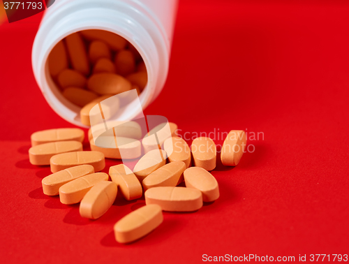 Image of Pills spilling out of pill bottle on red. Top view with copy space. 