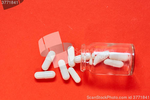 Image of Pills spilling out of pill bottle on red. Top view with copy space. 