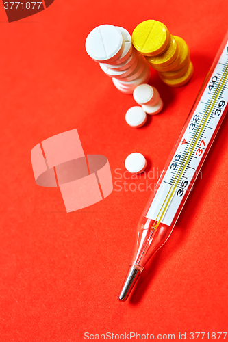 Image of Mercury thermometer and medical pills on background