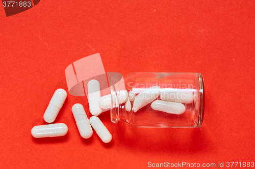 Image of Pills spilling out of pill bottle on red. Top view with copy space. 