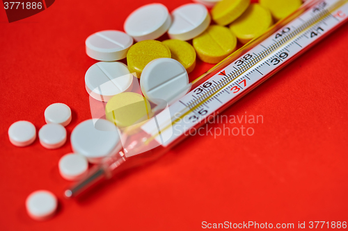 Image of Mercury thermometer and medical pills on background