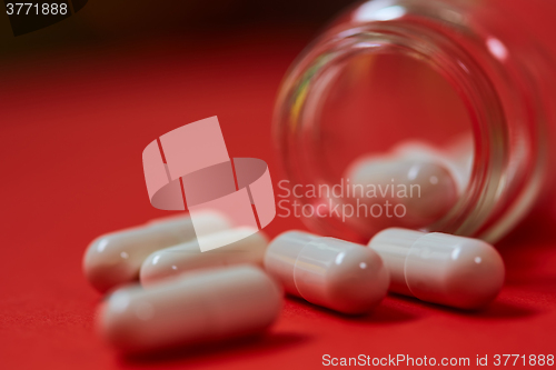 Image of Pills spilling out of pill bottle on red. Top view with copy space. 