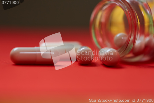 Image of Pills spilling out of pill bottle on red. Top view with copy space. 
