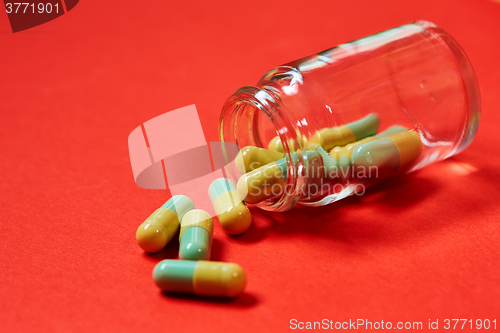 Image of Pills spilling out of pill bottle on red. Top view with copy space. 