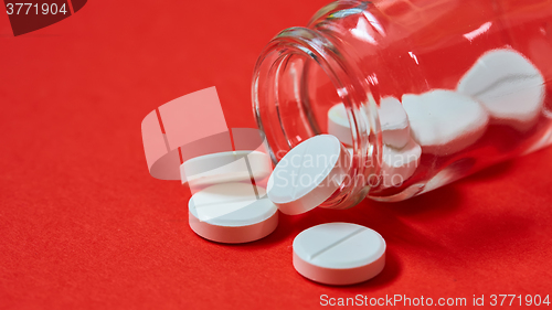 Image of Pills spilling out of pill bottle on red. Top view with copy space. 