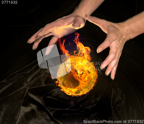 Image of burning crystal ball and hands