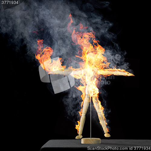Image of burning wooden doll on desktop