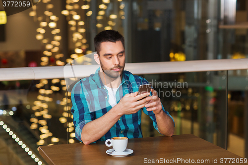 Image of man with smartphone and coffee at restaurant