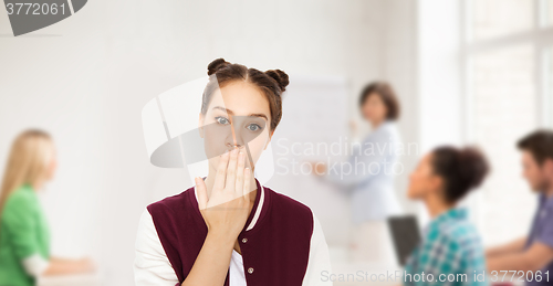 Image of confused student girl covering her mouth by hand