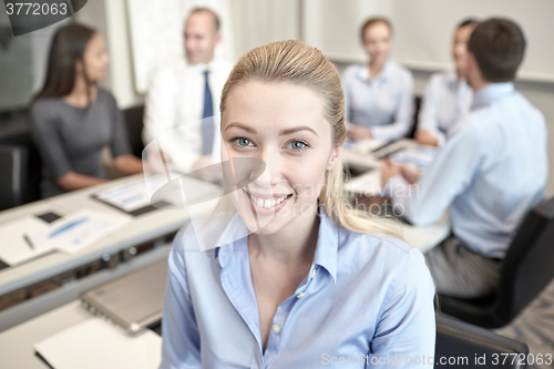 Image of group of smiling businesspeople meeting in office