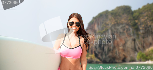 Image of smiling young woman with surfboard on beach