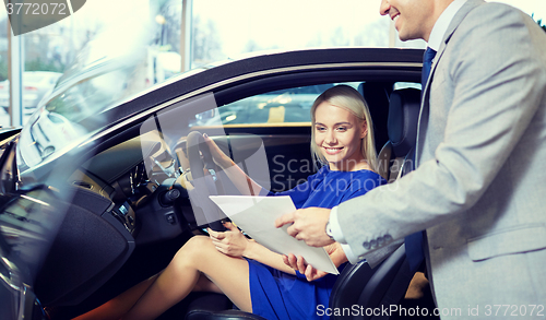 Image of happy woman with car dealer in auto show or salon