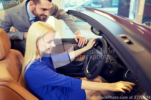 Image of happy couple buying car in auto show or salon