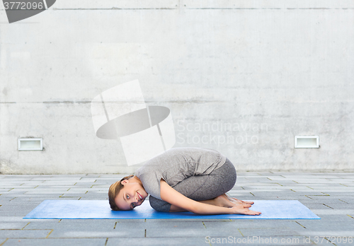 Image of happy woman making yoga in child pose on mat