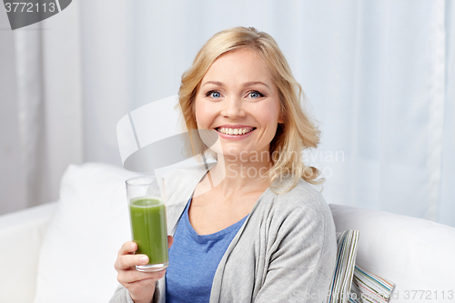 Image of happy woman drinking green juice or shake at home