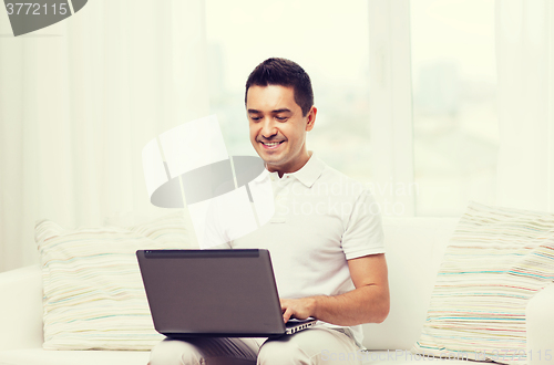 Image of happy man working with laptop computer at home
