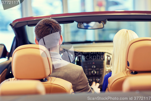 Image of couple sitting in cabriolet car at auto show