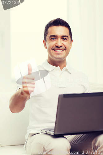 Image of happy man working with laptop computer at home