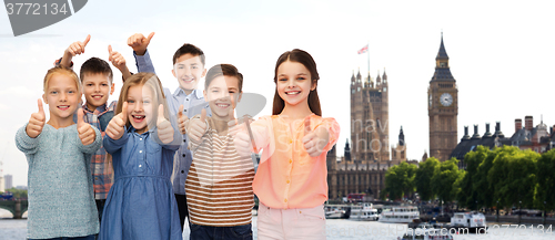 Image of happy children showing thumbs up over london