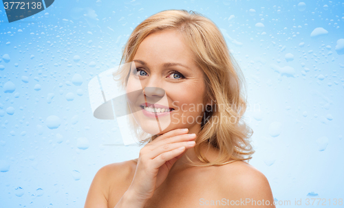 Image of smiling woman with bare shoulders touching face