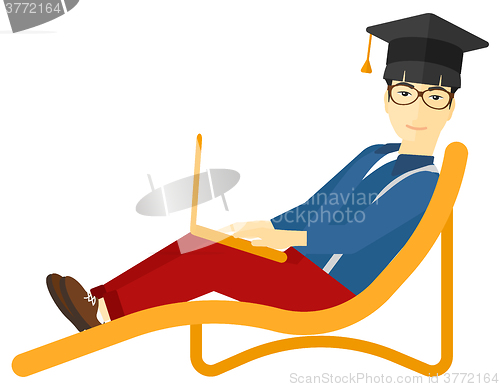 Image of Graduate lying on chaise lounge with laptop.