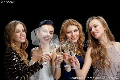 Image of happy women clinking champagne glasses over black