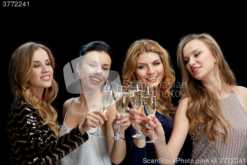 Image of happy women clinking champagne glasses over black