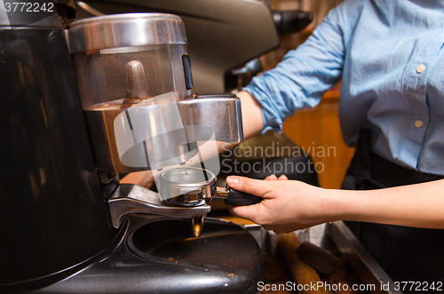 Image of close up of woman making coffee by machine at cafe
