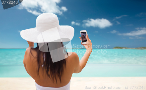 Image of woman taking selfie with smartphone on beach