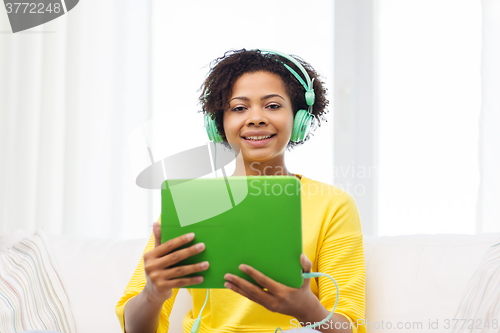 Image of happy african woman with tablet pc and headphones