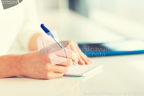 Image of close up of hands with pen writing to notepad