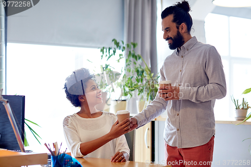 Image of happy man bringing coffee to woman in office