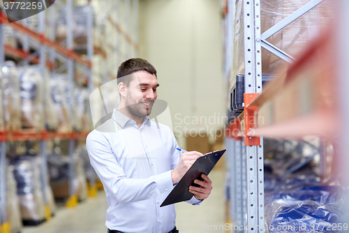 Image of happy businessman with clipboard at warehouse