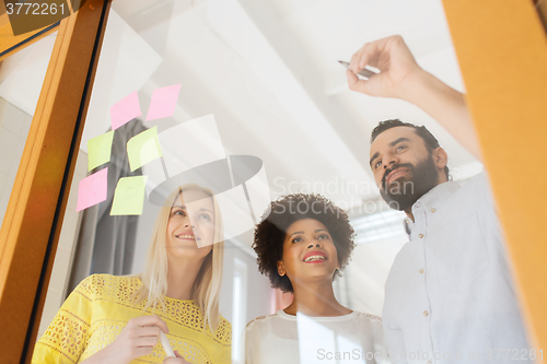 Image of happy creative team writing on stickers at office