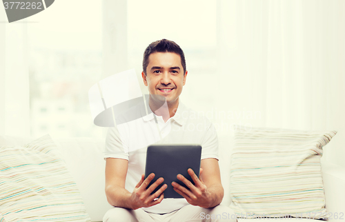 Image of smiling man working with tablet pc at home