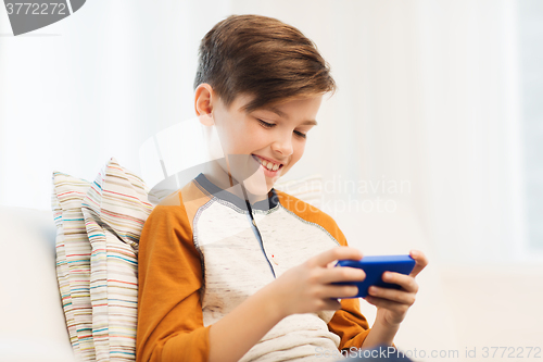 Image of boy with smartphone texting or playing at home