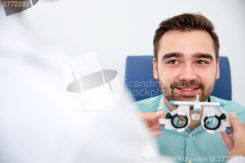 Image of optician with trial frame and patient at clinic