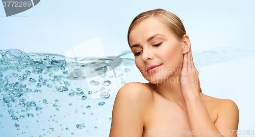 Image of smiling young woman touching her neck