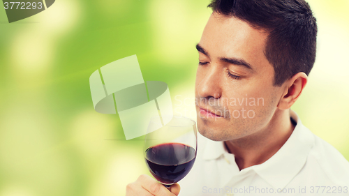 Image of happy man drinking red wine from glass