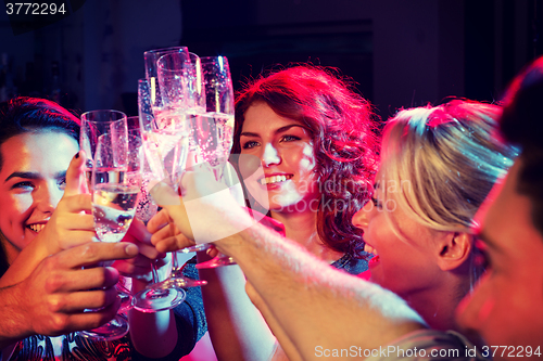 Image of smiling friends with glasses of champagne in club