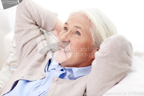 Image of happy senior woman resting on sofa at home